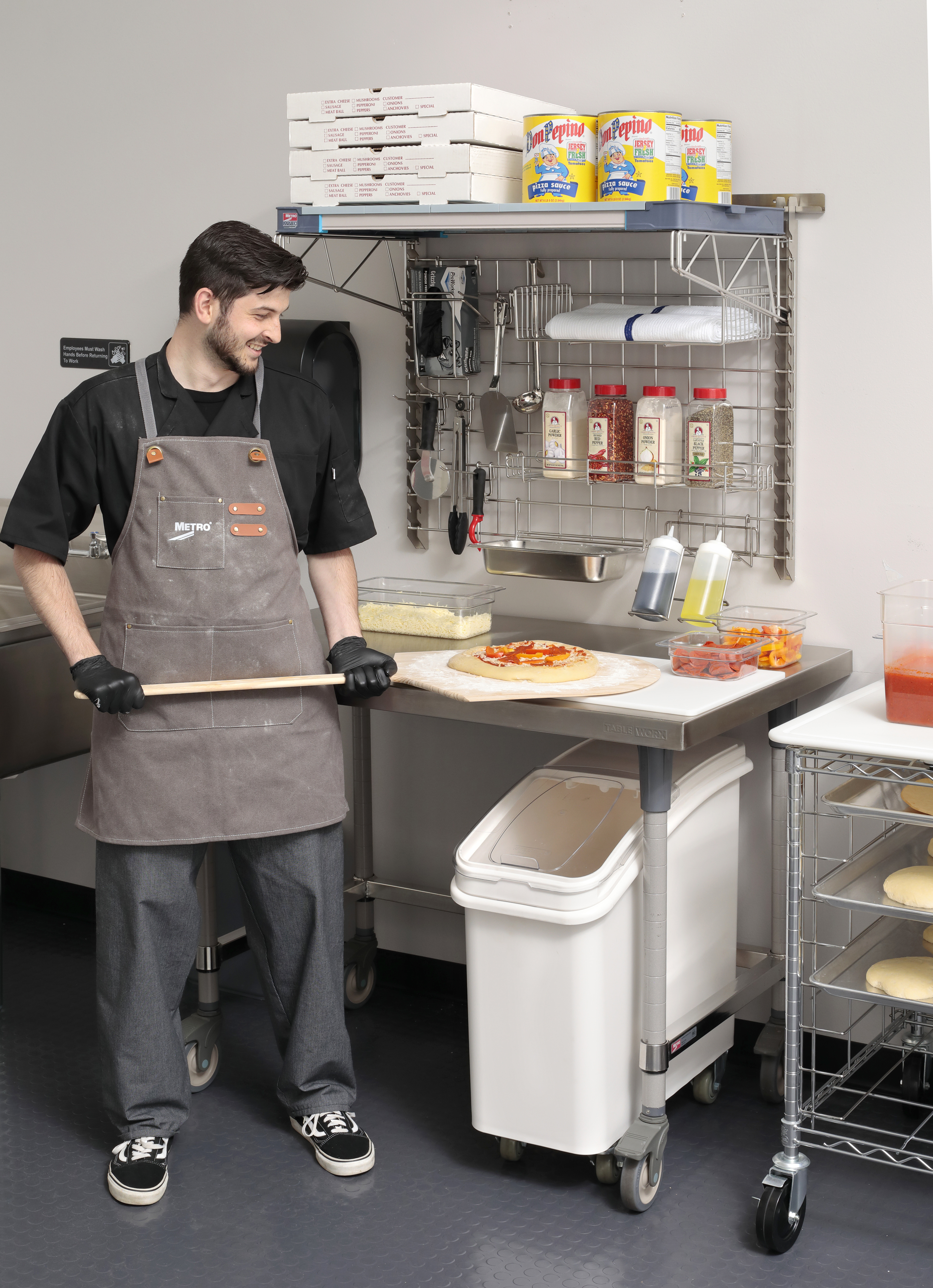 Metro SmartWall wall shelving system complete pizza prep kit mounted above a TableWorx stainless steel work table
