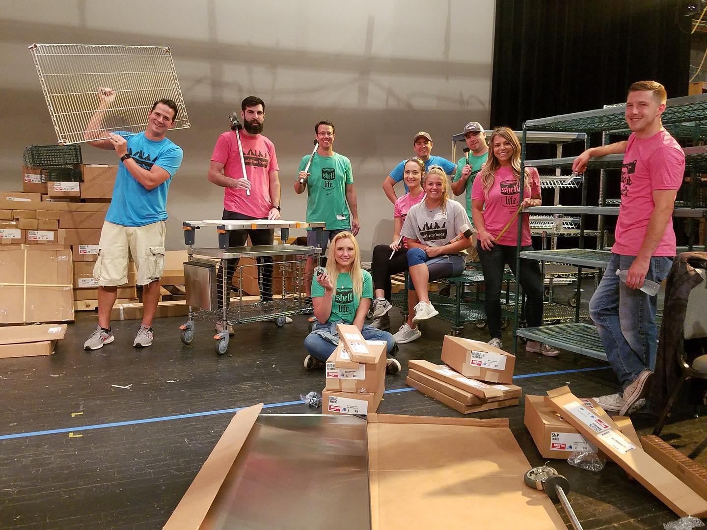 Photograph of people posing around dry racks and cardboard boxes.