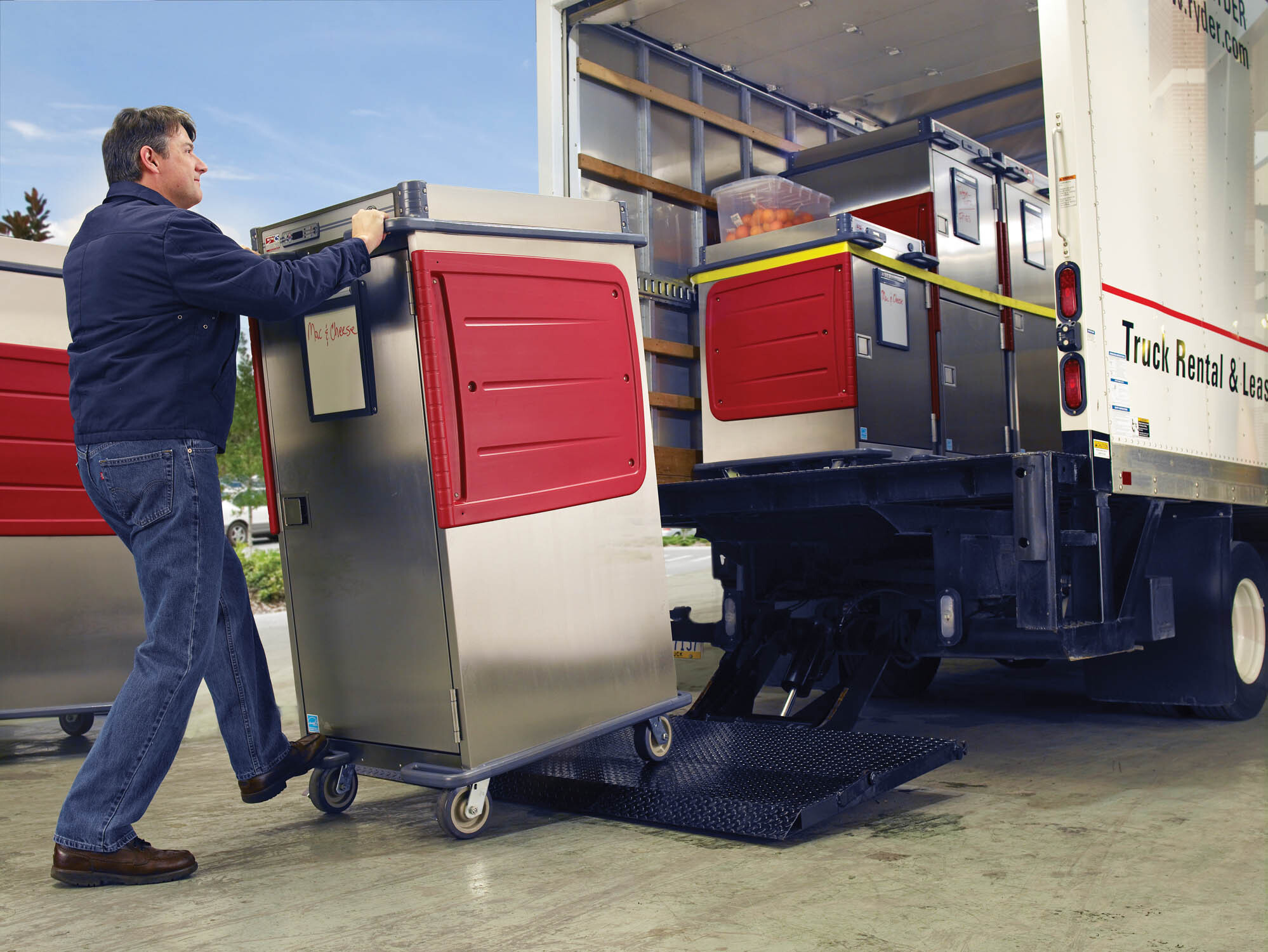 A man loading a Metro C5 T-series transport cabinet into the back of a box truck