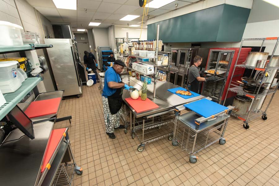 Cooks prepare food within an open kitchen.