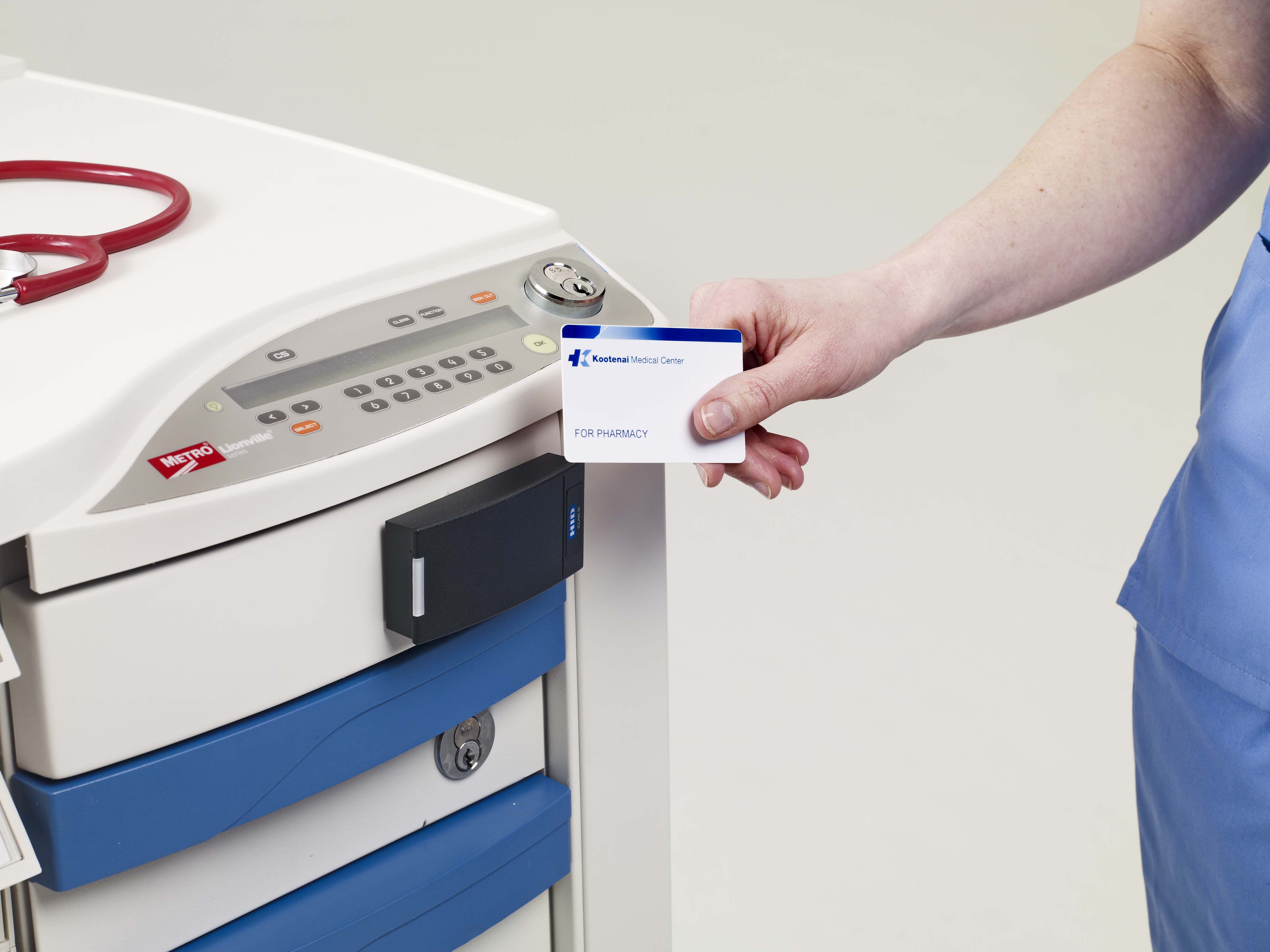Outstretched arm holding a medical card against a card reader attached to  a locked medication cart.