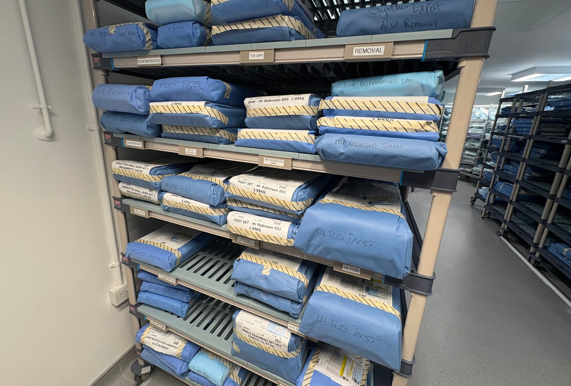 A MetroMax plastic shelf stocked with sterile wrapped packages in a a hospital SPD 