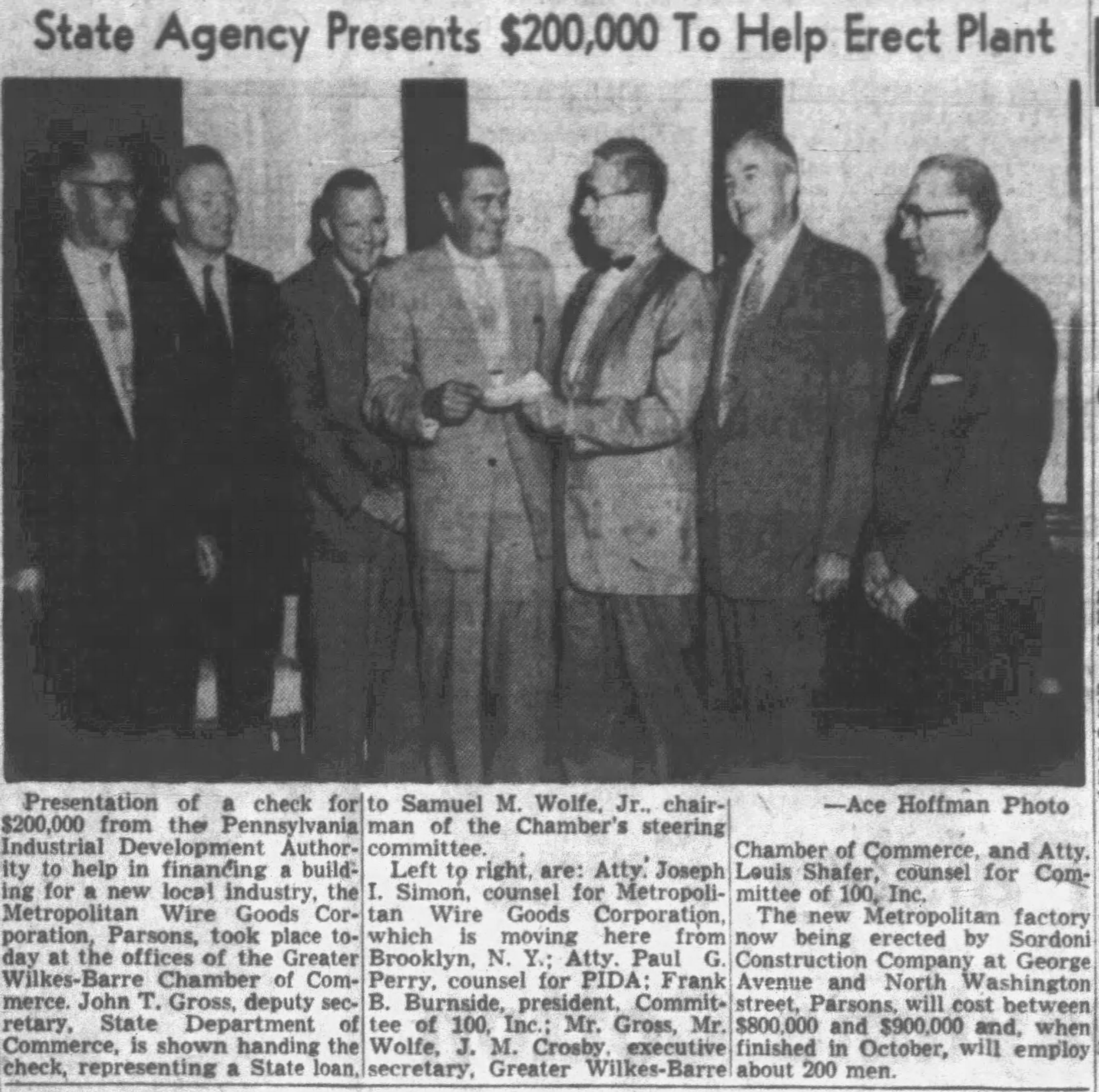 Newspaper clipping displaying a black and white photograph showing of men wearing suits standing next to one another